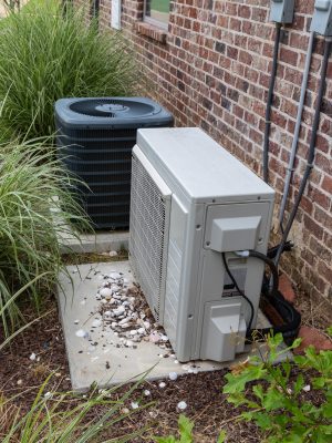 Regular home HVAC air conditioner system and mini-split next to each other. HVAC Air Conditioner Compressor and a Mini-split system together next to each other, next to a brick home.