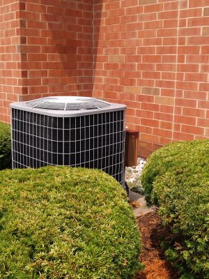 Air conditioner with brick building in background Outside residential air conditioning unit by a red brick building.